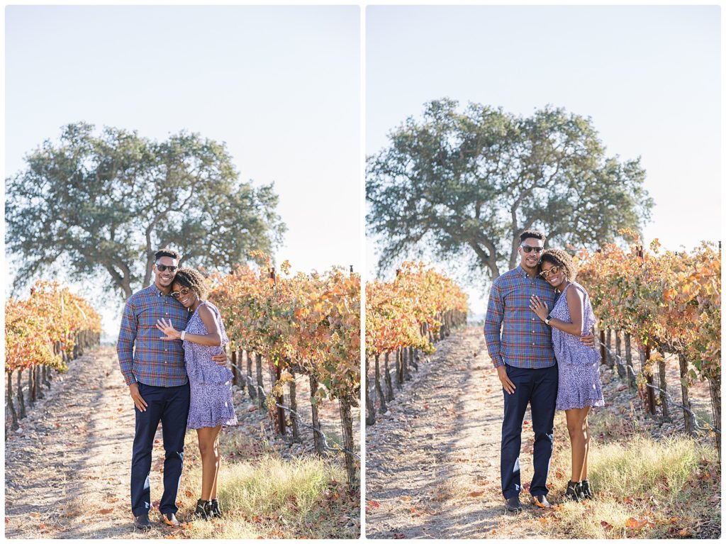 recently engaged couple admiring their ring and smiling at the camera while in a vineyard