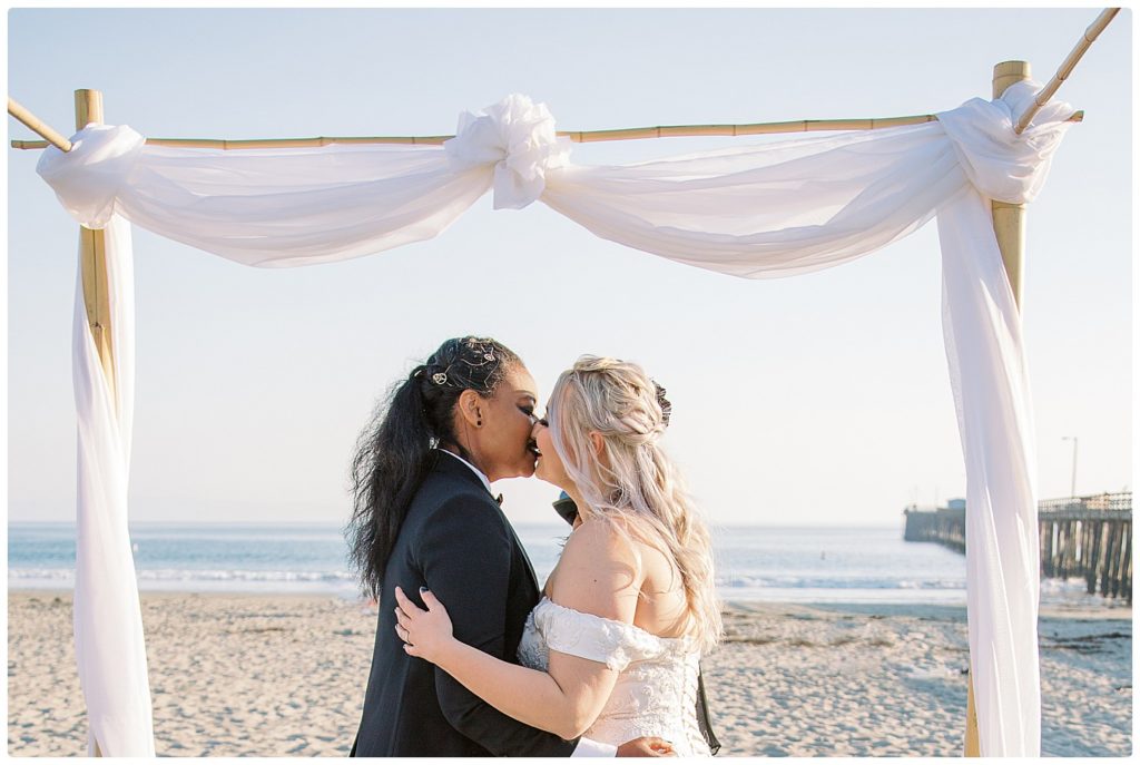 2 brides kissing because they are legally wed during their steampunk beach wedding California