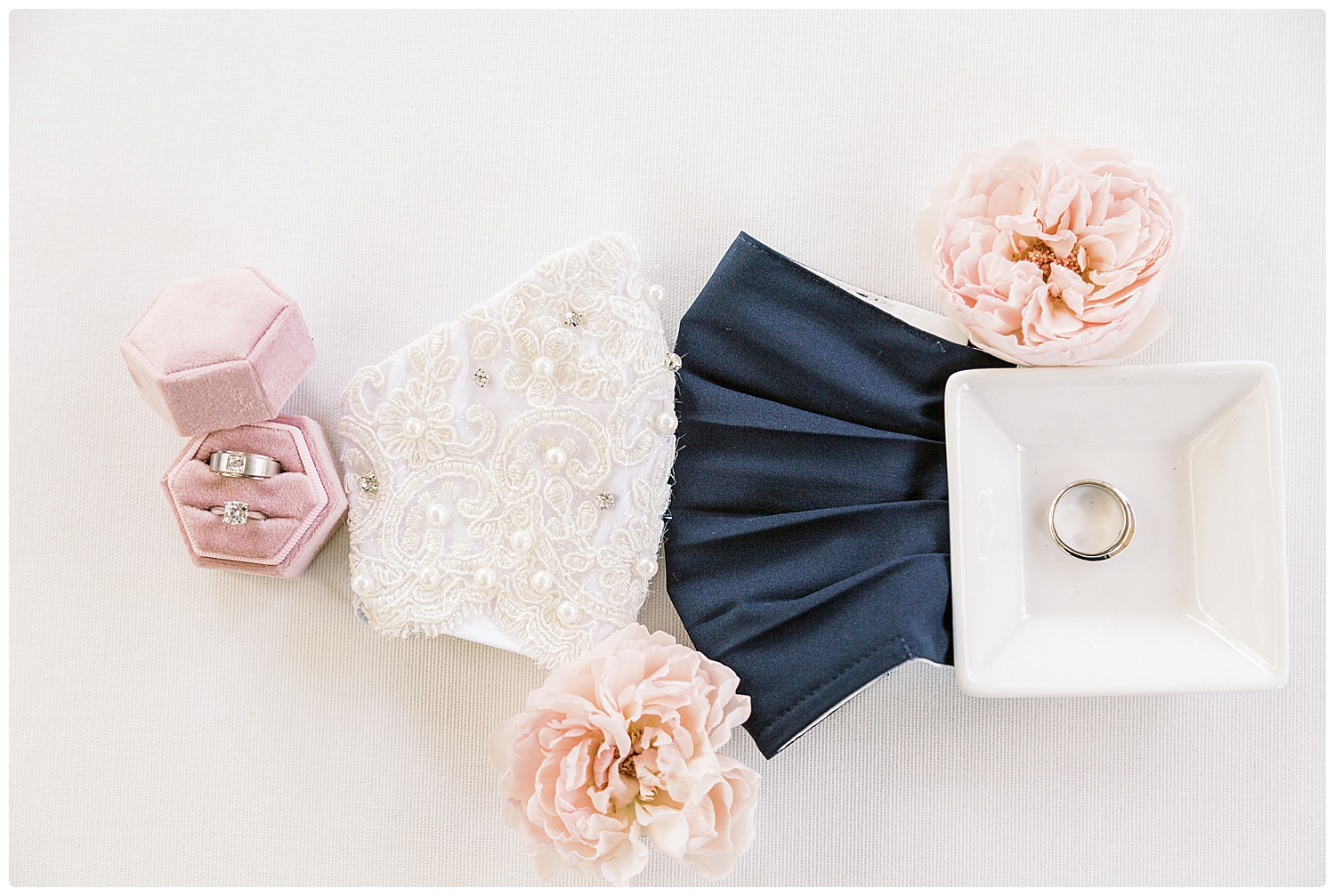 bride and groom masks and wedding rings and floral flatlay