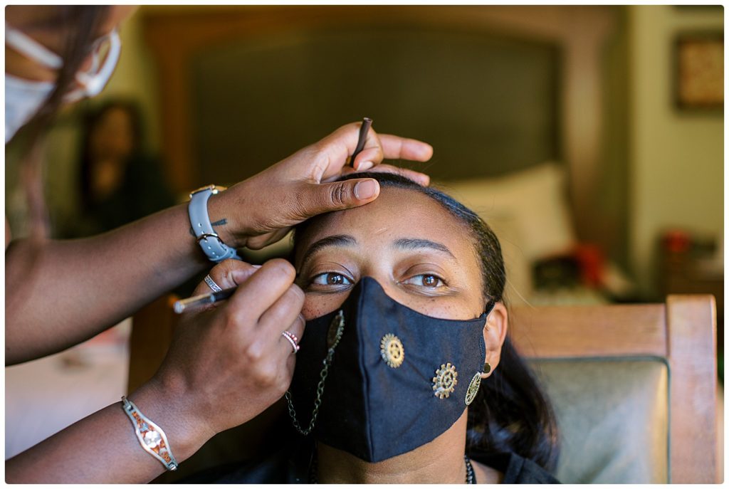 bride getting makeup done wearing a mask