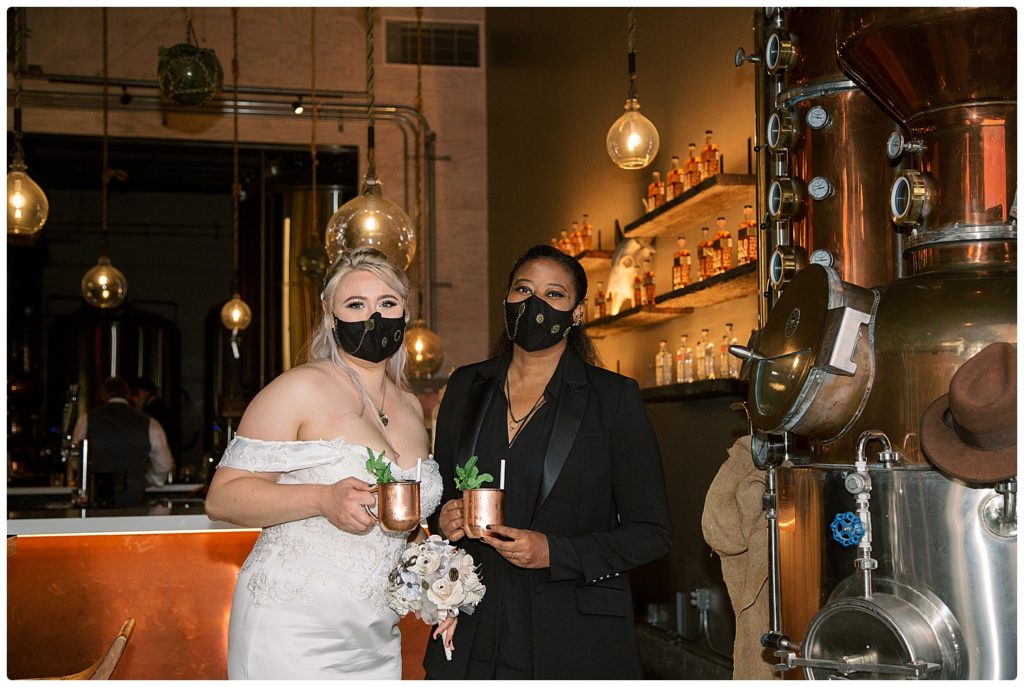 2 brides posing with drinks to celebrate