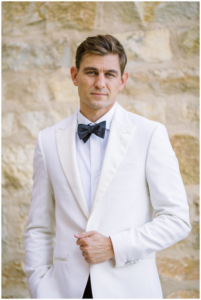 husband looking at camera no smile in white tux