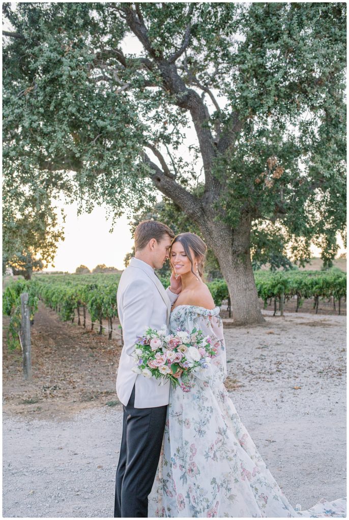husband gently caressing brides cheek in winery