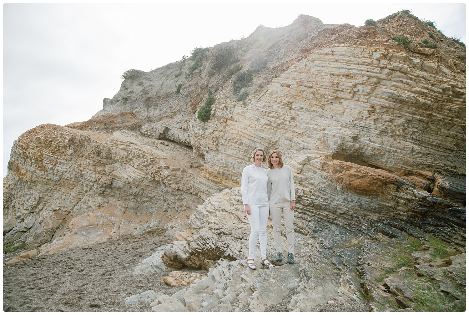 Two brides on rugged rocks at Montano del Oro State beach beach wedding photos