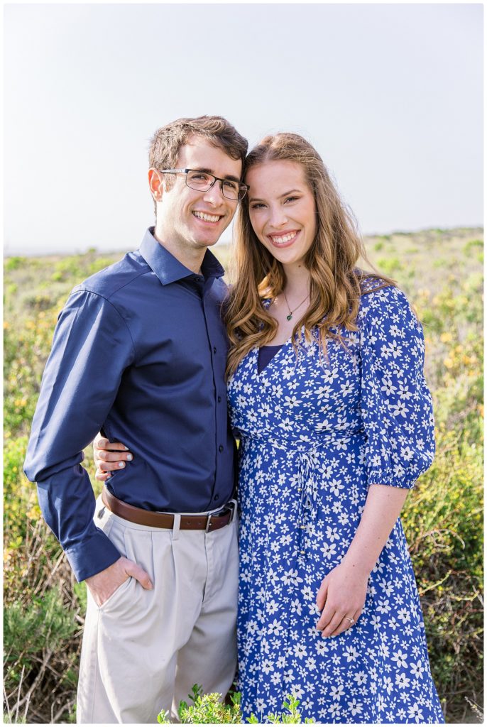 engaged couple smiling in a field