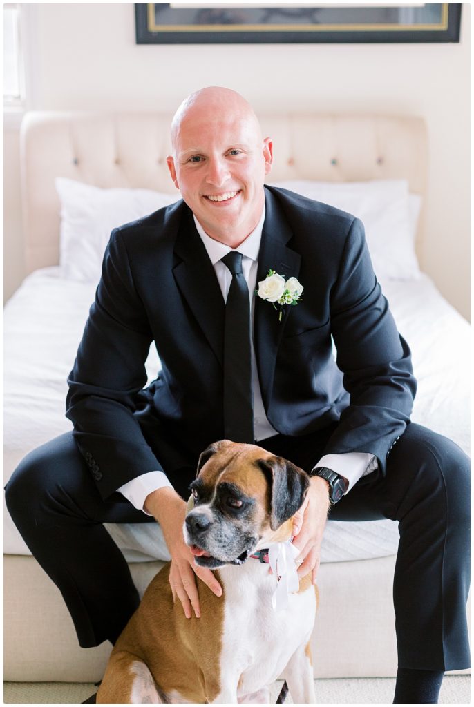 groom smiling on the bed while with his dog