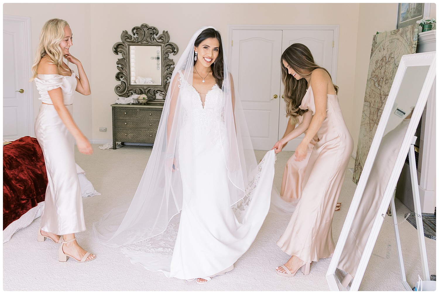 bridesmaids helping bride with her gown trans and veil