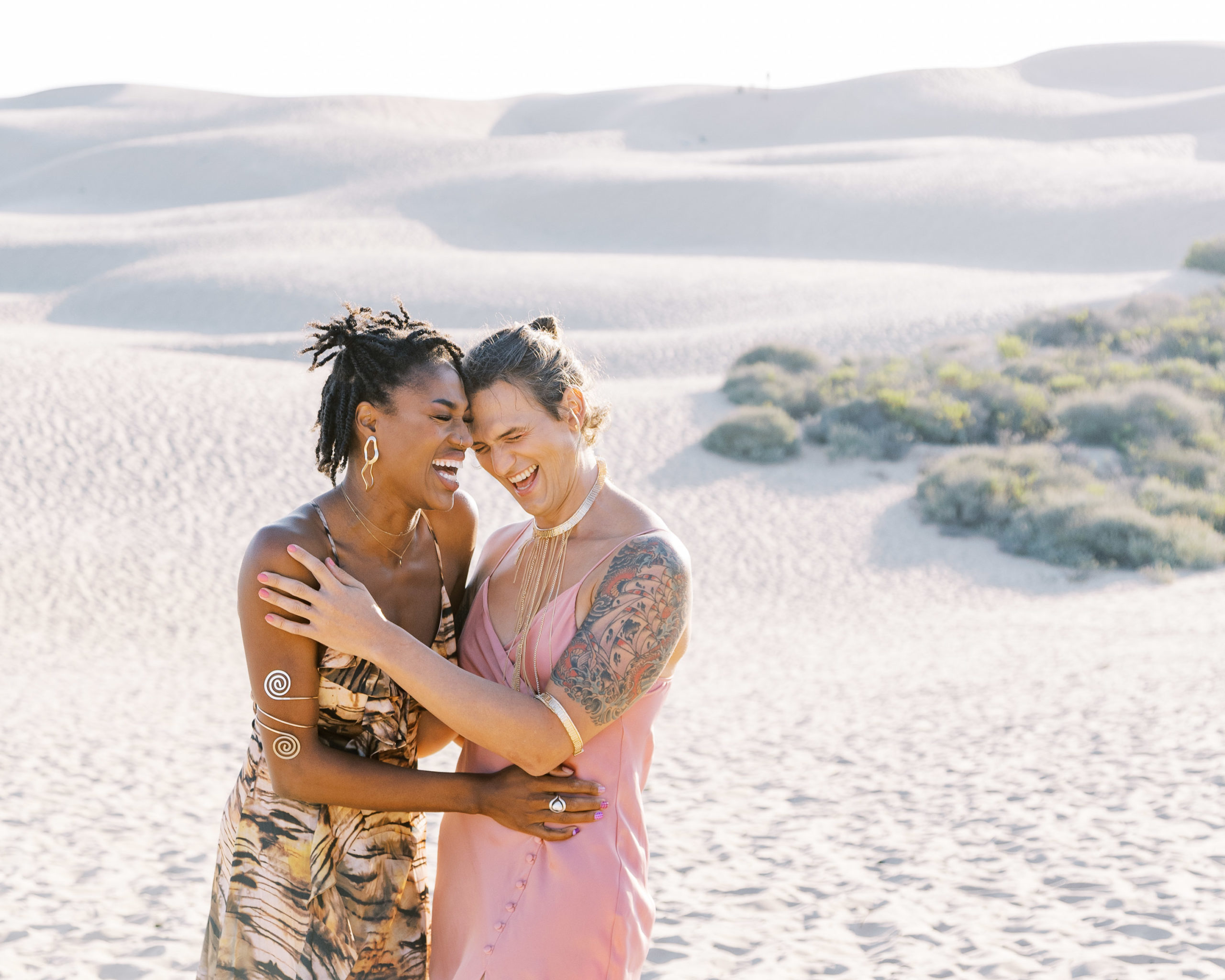 2 women laughing in the sand