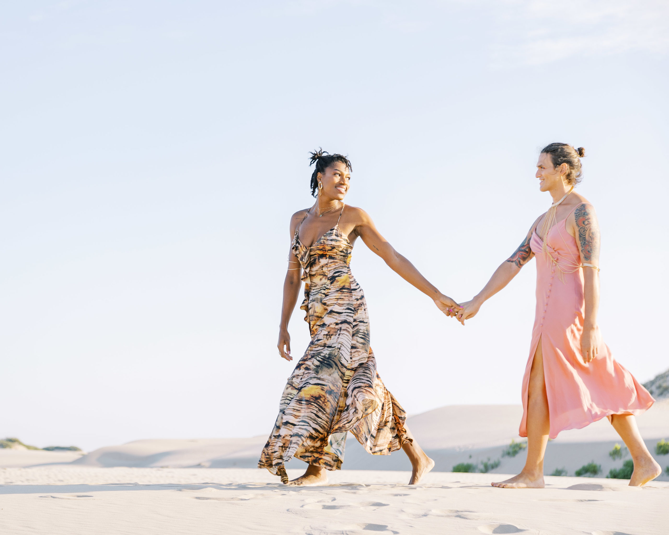 2 women walking hand in hand in the sand