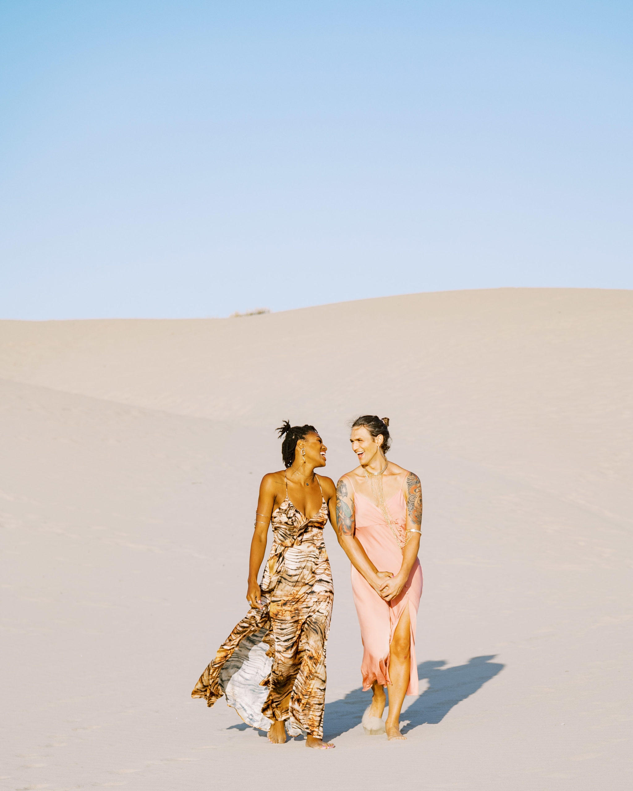Two women holding hands and walking in the sand