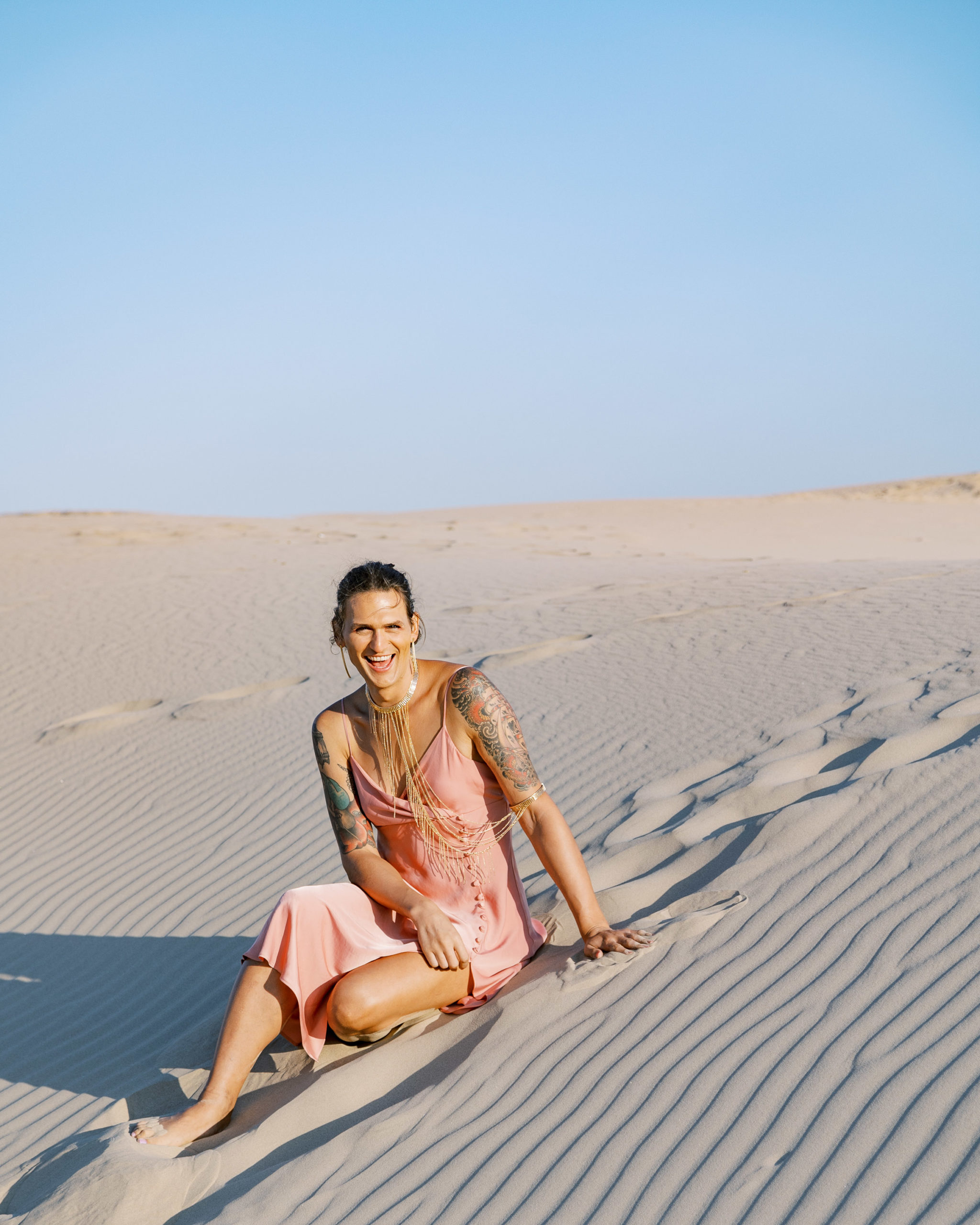 Woman sitting int he sand smiling at camera