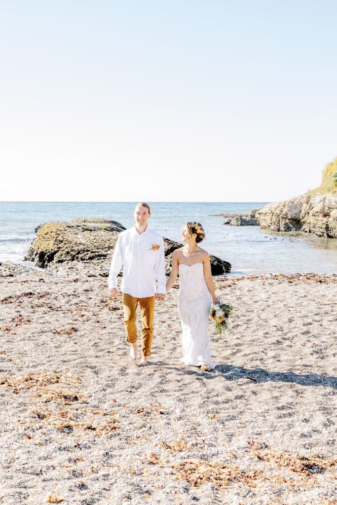 boho beach wedding - bride and groom walking in the sand