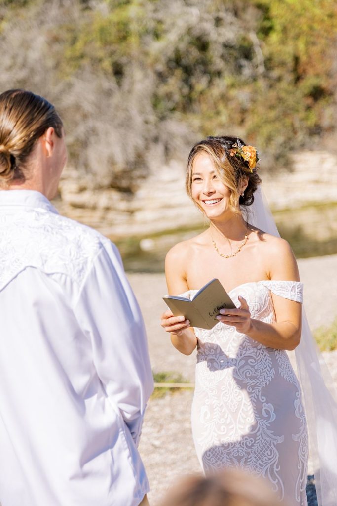 bride smiling as she reads her vows to her husband at boho wedding