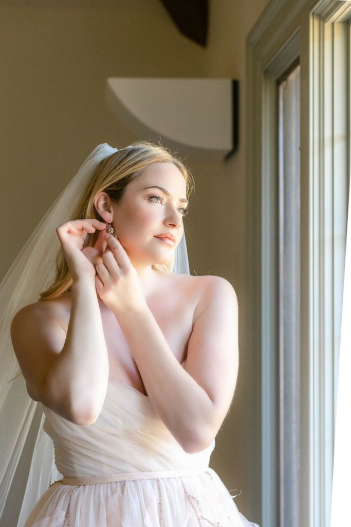 bride putting on her wedding earrings -getting ready pictures
