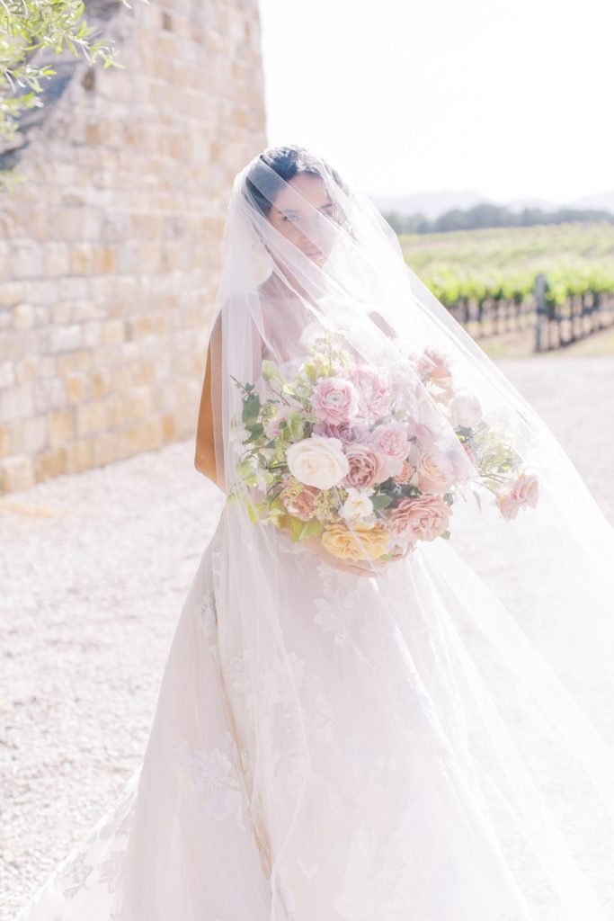 bride covered with veil and holding bouquet